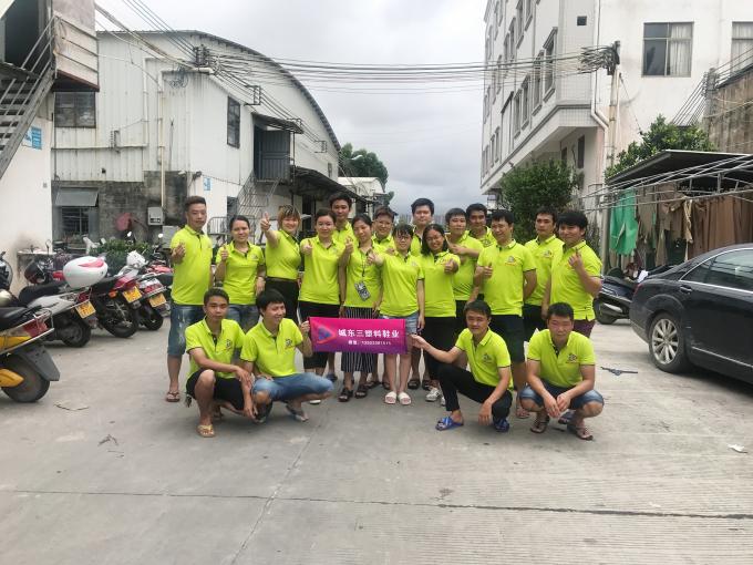 Group photo of Chengdong San Footwear staff wearing matching lime-green uniforms, holding banner with company name “åä¸ä¸å¡æéä¸” and contact info, posing outdoors near factory building.
